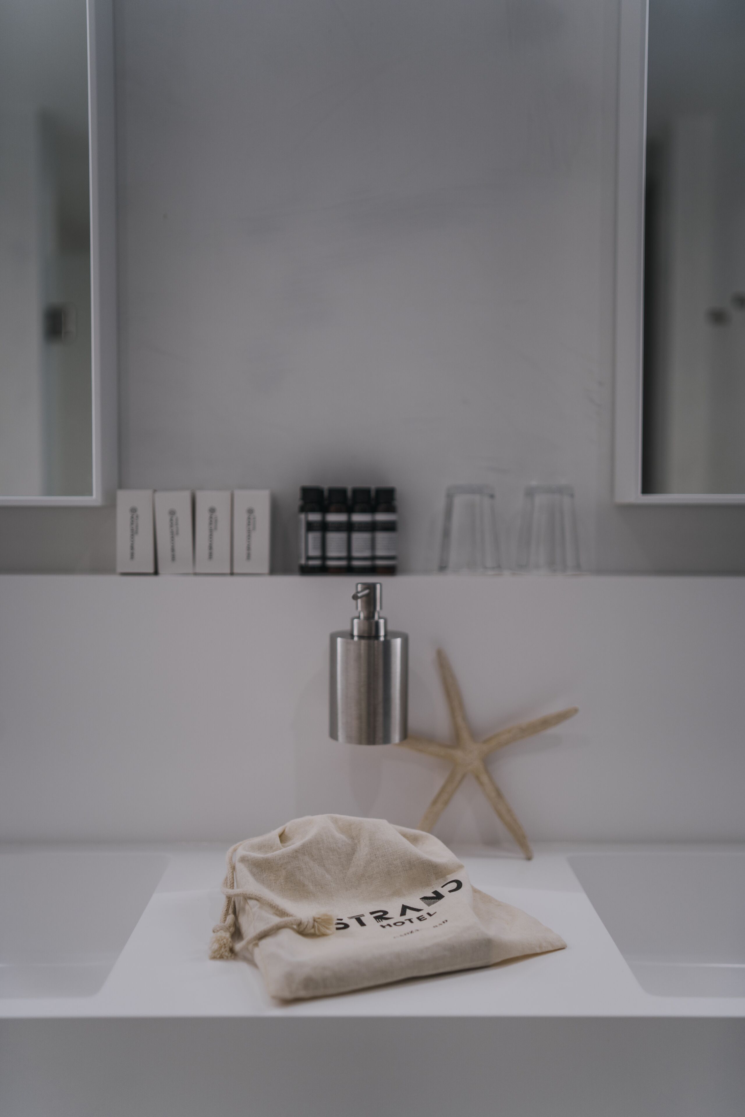 A bathroom with a white sink, a starfish decoration, and a towel with "GRAND HOTEL" text.
