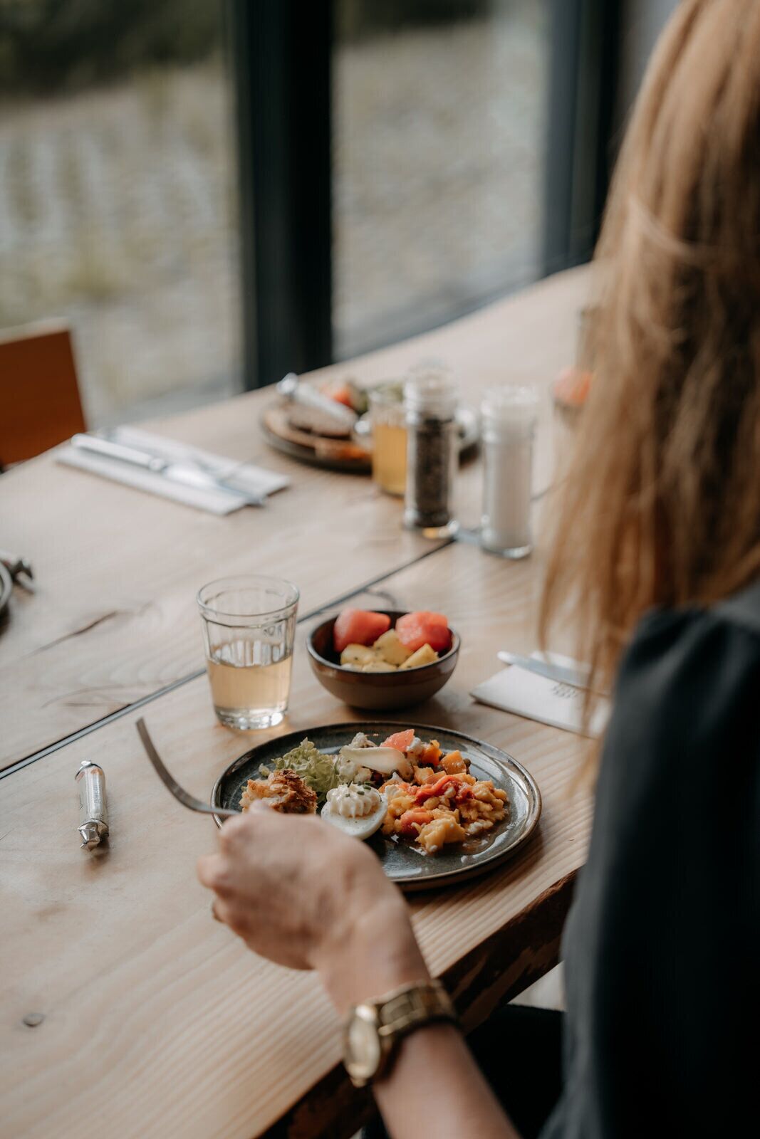 Een eettafel met een maaltijd, zout- en peperstel, een glas water en een vork.