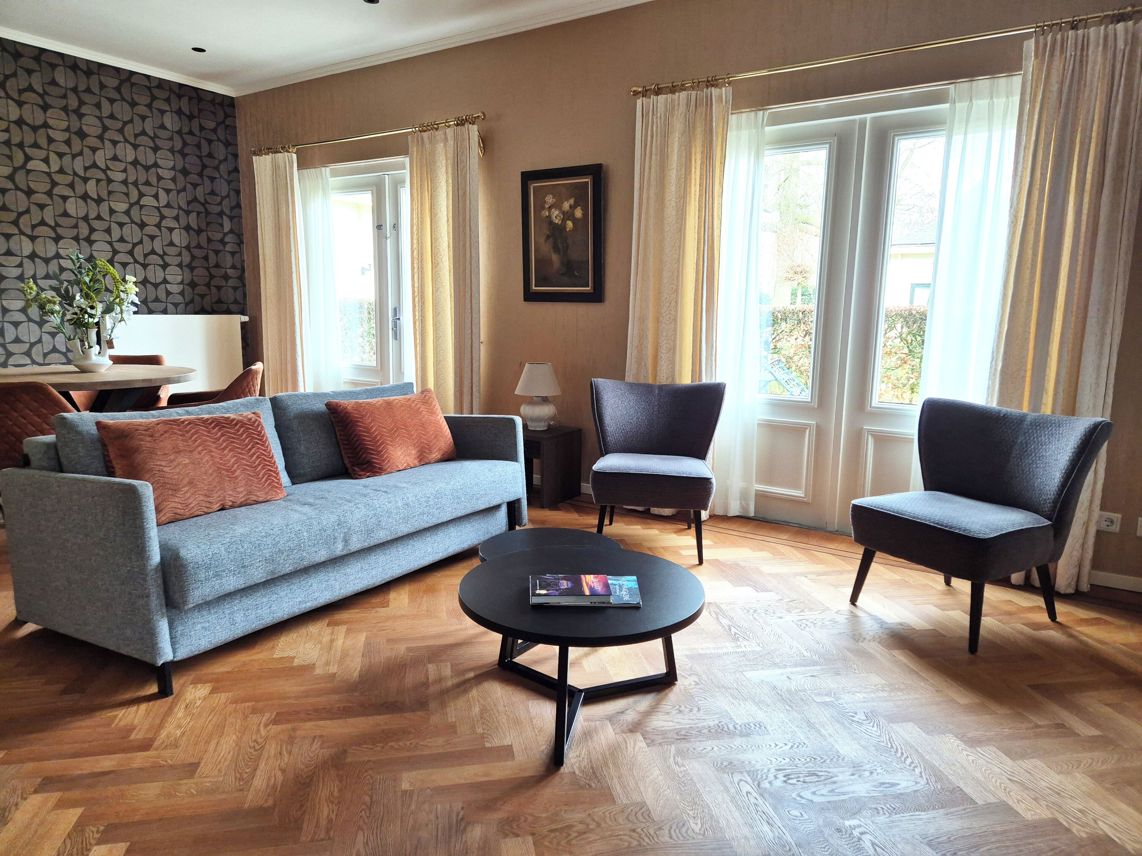 A living room with a sofa, two armchairs, a coffee table, and a painting on the wall.