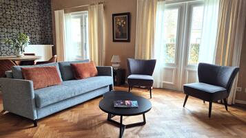 A living room with a sofa, two armchairs, a coffee table, and a painting on the wall.