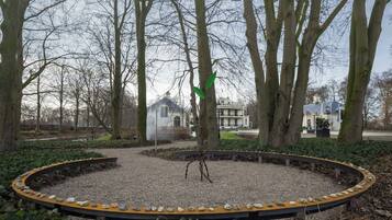 Een park met een rond grindgebied, banken en bomen.