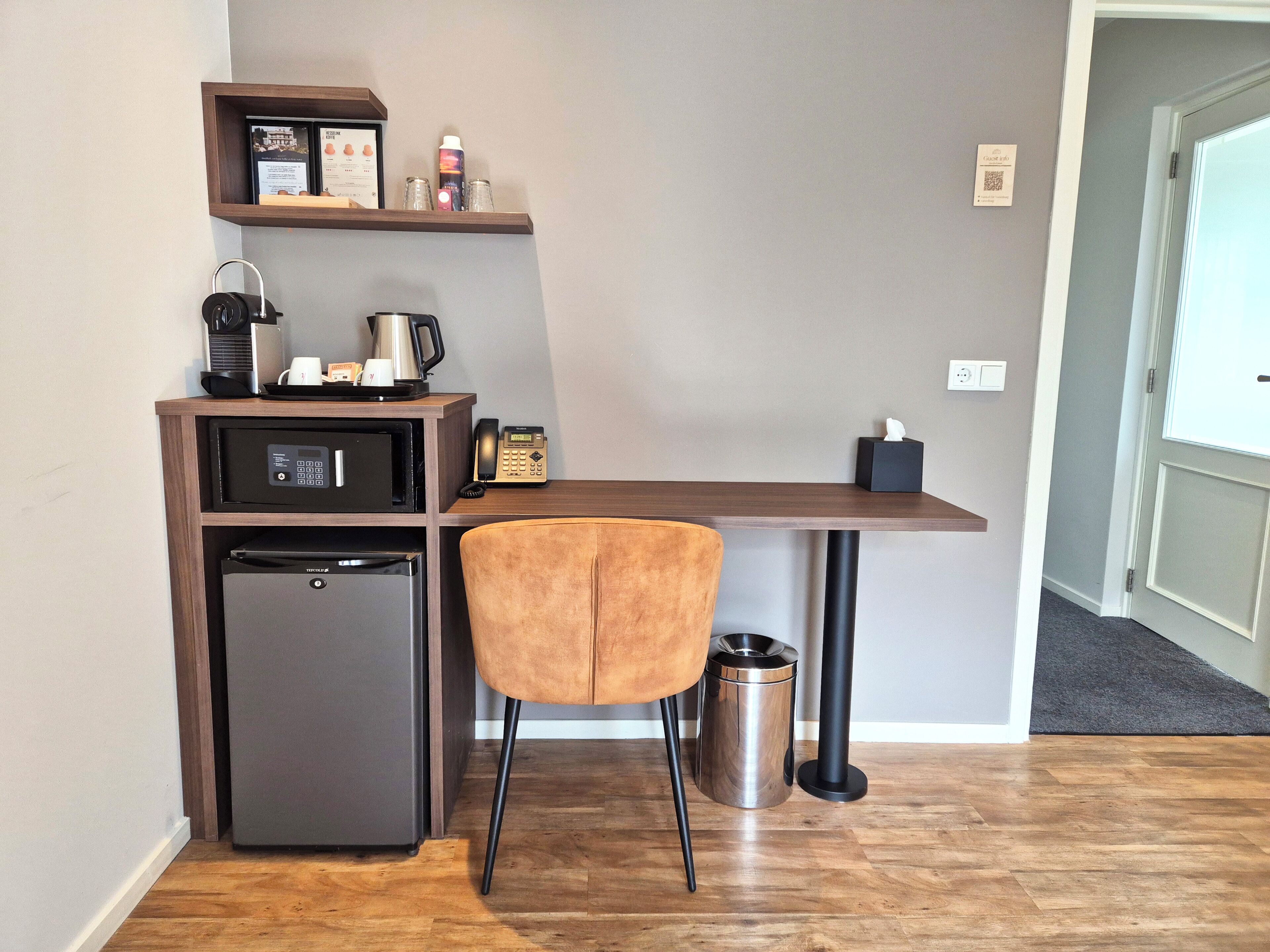 Eine kleine Küchenzeile mit Kühlschrank, Mikrowelle, Kaffeemaschine und einem Regal mit Gegenständen.