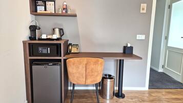 Eine kleine Küchenzeile mit Kühlschrank, Mikrowelle, Kaffeemaschine und einem Regal mit Gegenständen.