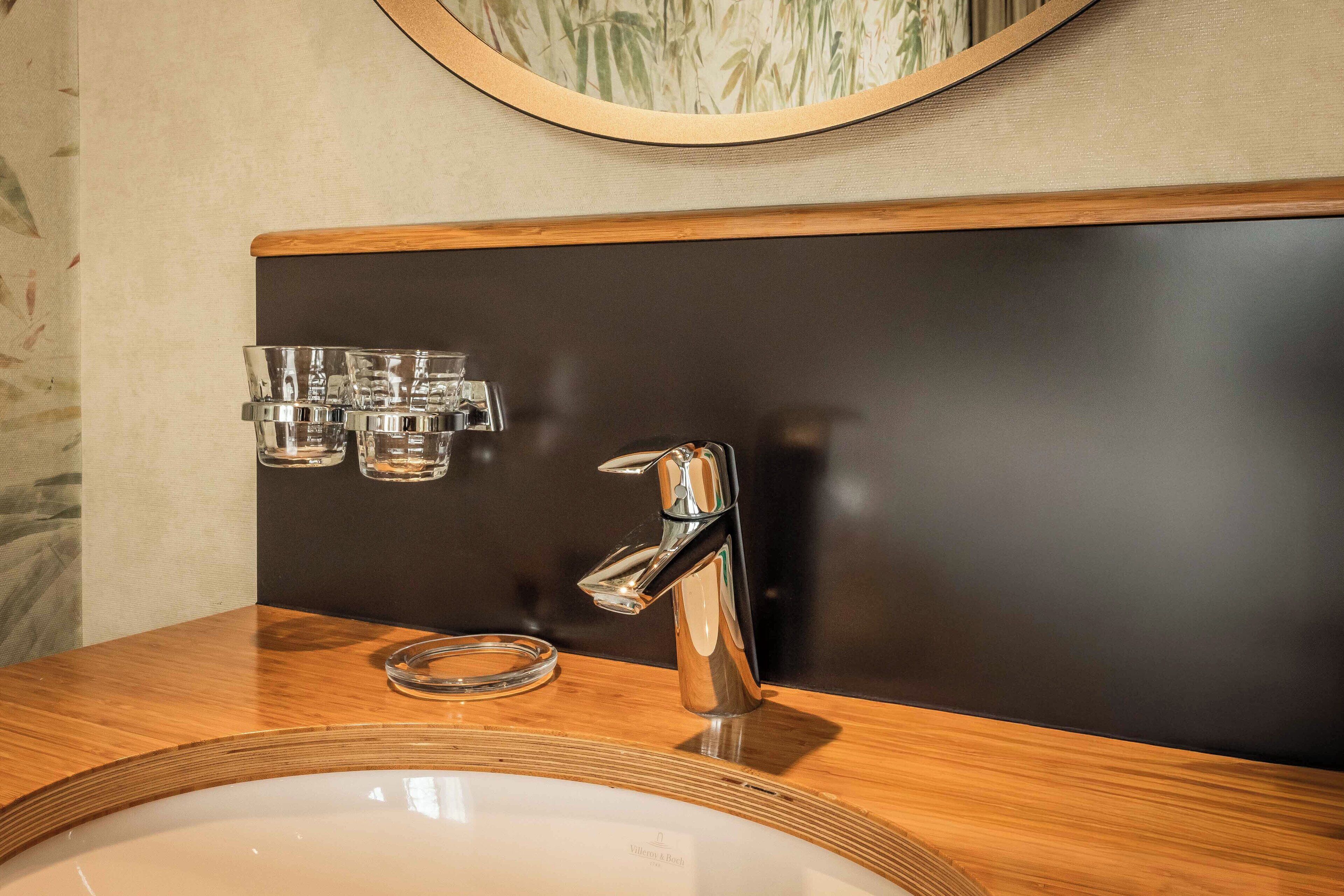 A bathroom with a wooden vanity, a chrome faucet, and a mirror above the sink.