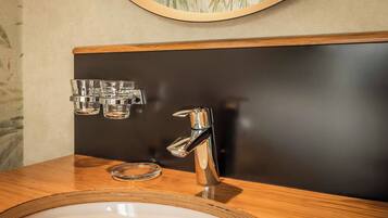 A bathroom with a wooden vanity, a chrome faucet, and a mirror above the sink.