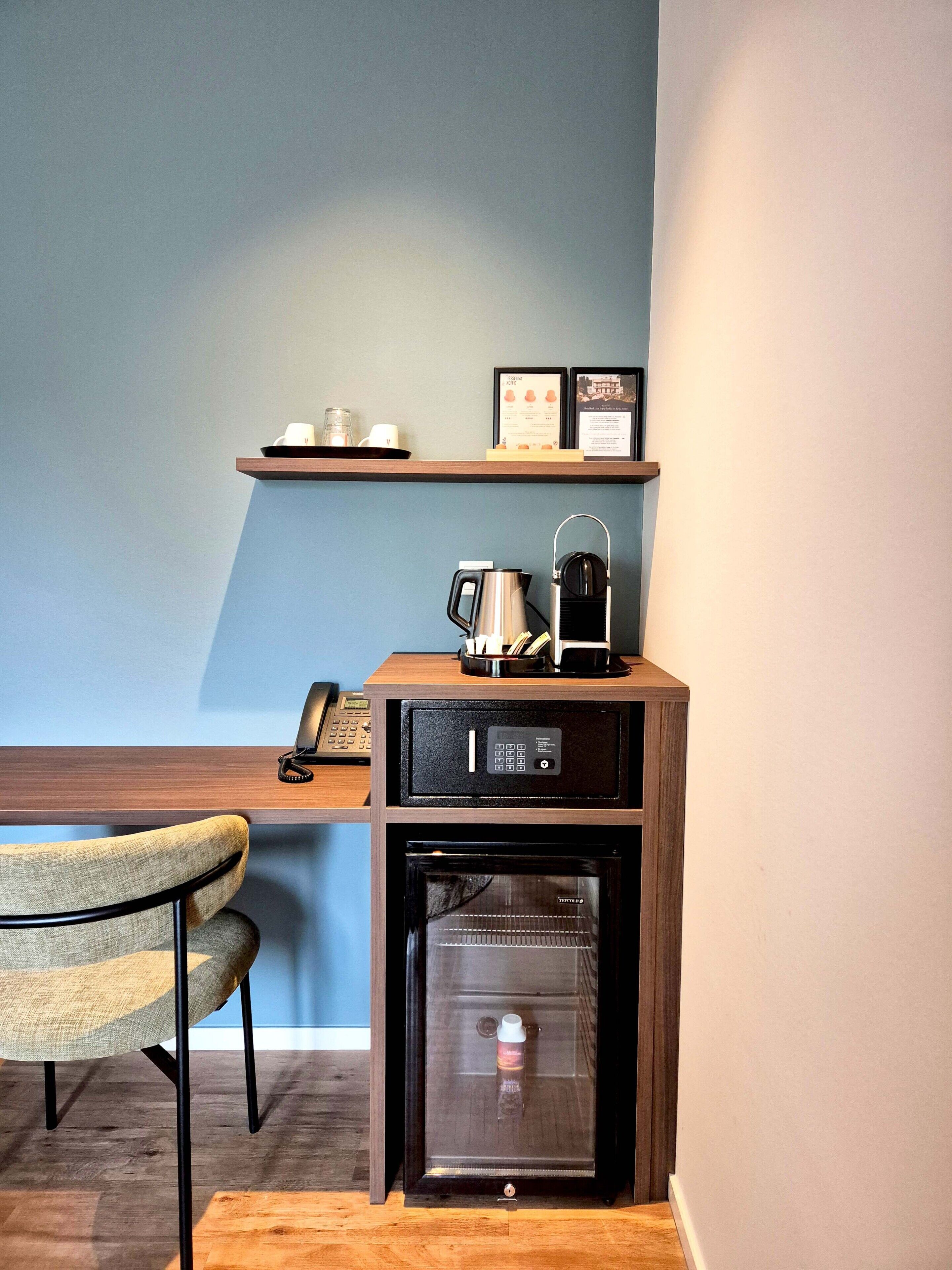 Een kleine kitchenette met een koffiezetapparaat, een minibar en een telefoon op een houten aanrecht.