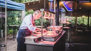 Un espacio al aire libre para comidas con una estación de parrilla, mesas y sillas.