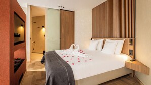 Una habitación de hotel con una cama, cabecero de madera, mesita de noche con lámpara y un espejo en la pared.