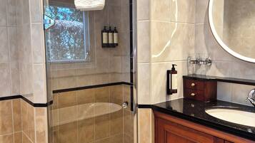 A modern bathroom with a glass-enclosed shower, a vanity with a sink, and a large mirror.