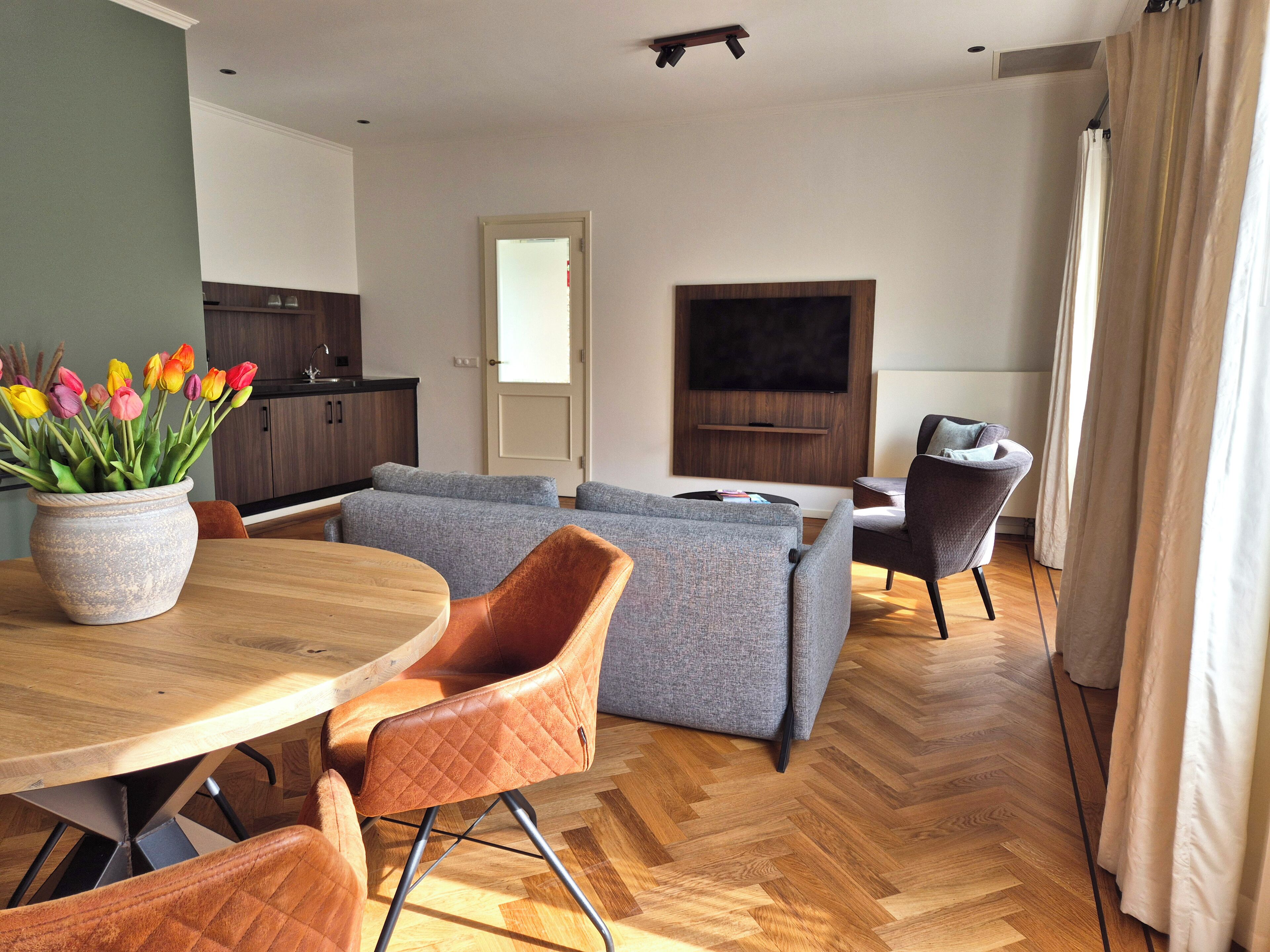 Una sala de estar moderna con un sofá, sillas, un televisor y una zona de comedor con mesa y sillas.