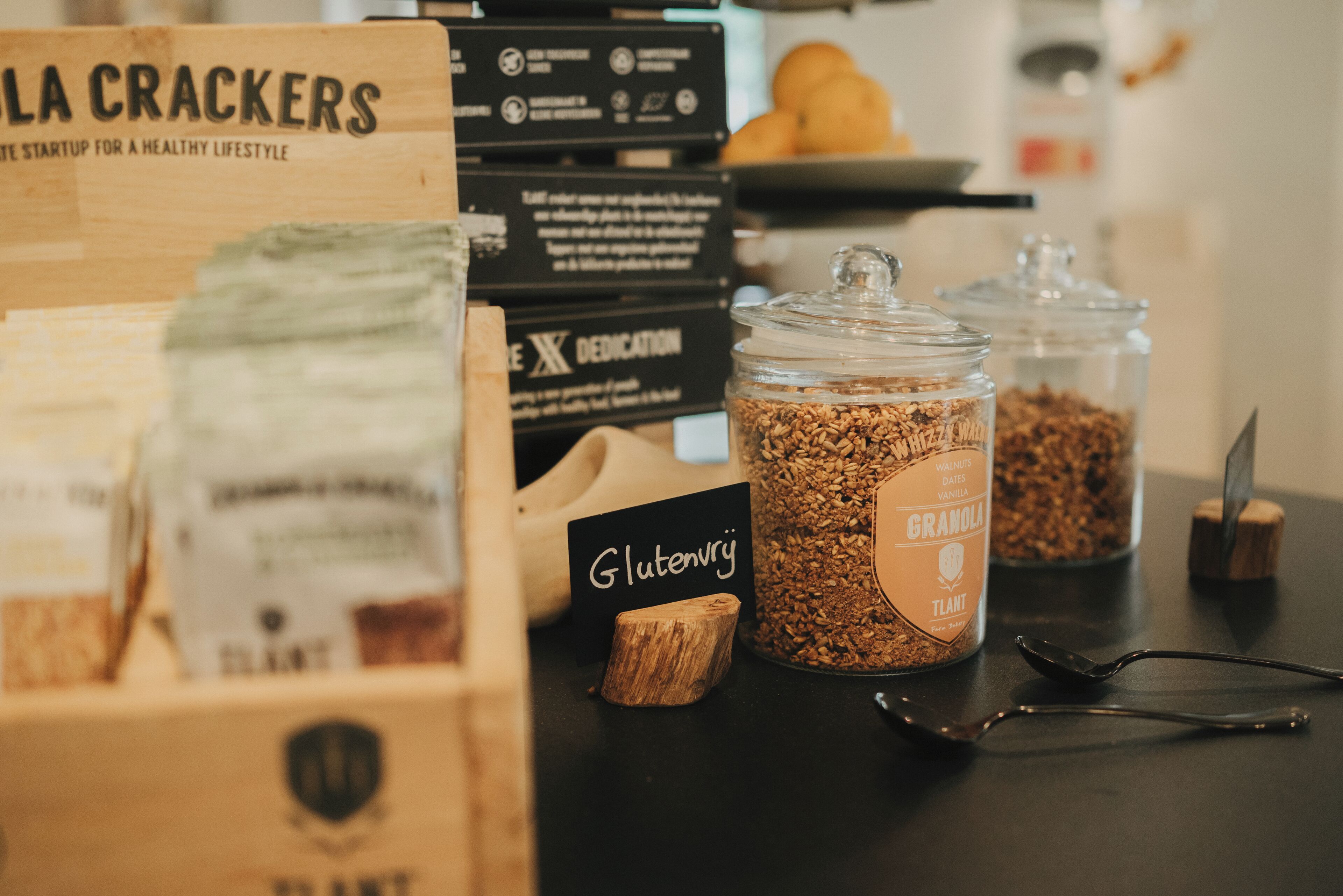 A table with various food items, including boxes labeled 'La Crackers' and 'Gluten Free', and jars of granola.