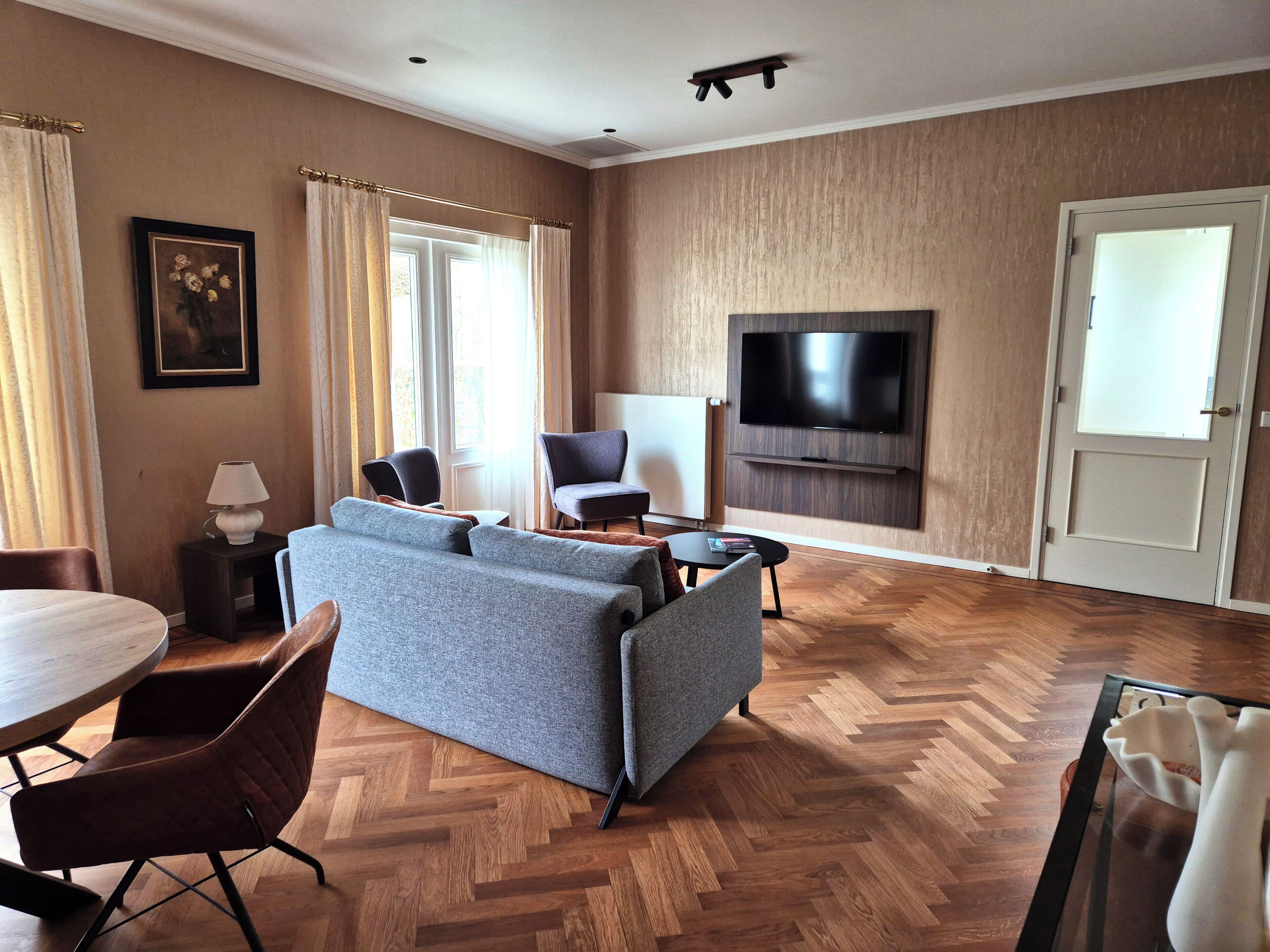 Una sala de estar moderna con un sofá, sillas, un televisor y un comedor.