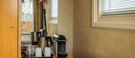 A coffee station with a coffee maker, cups, and a tray.