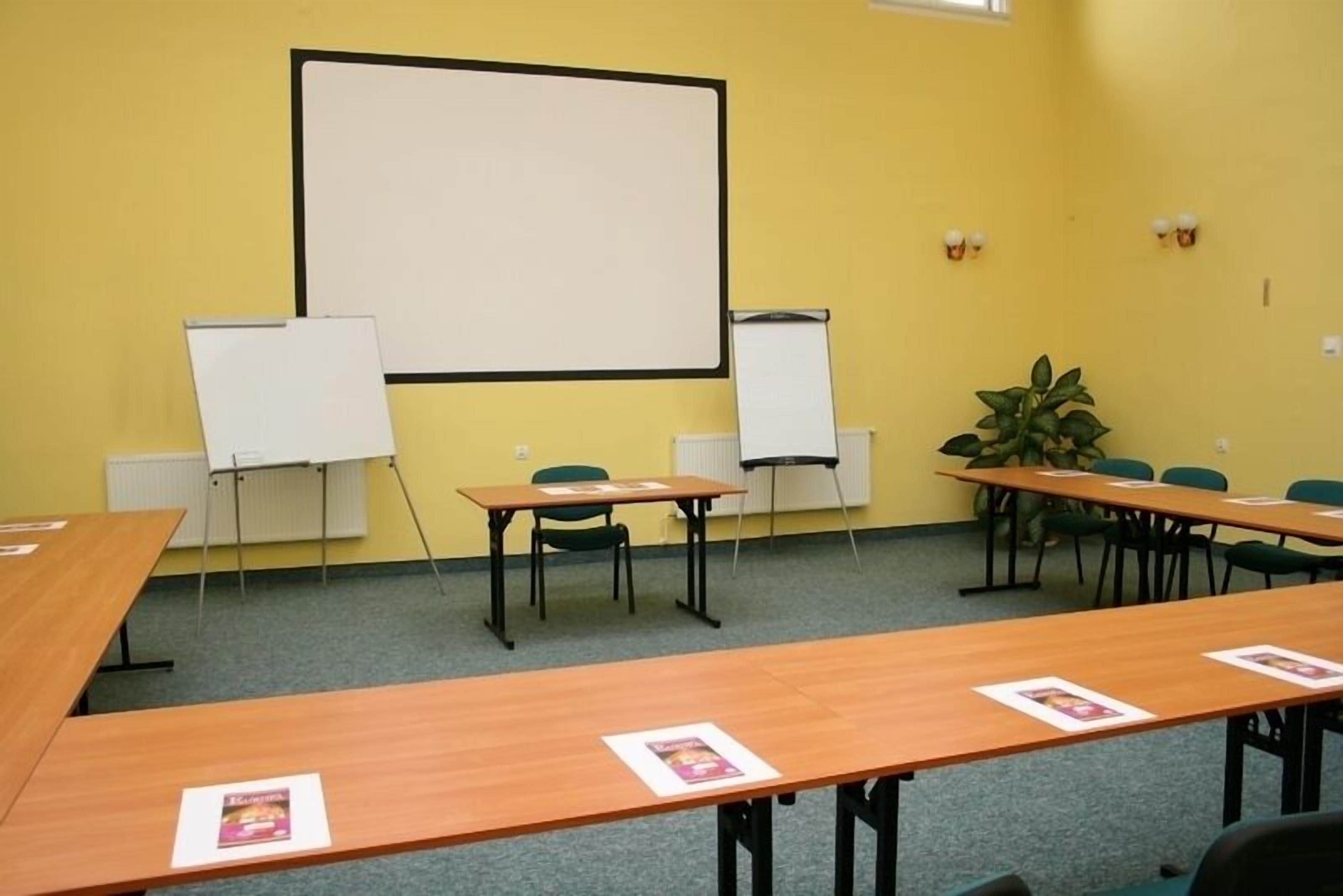 A conference room with a large whiteboard, two whiteboard stands, and several tables with chairs.