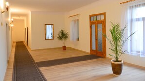 A spacious room with wooden flooring, a potted plant, and a door with a frosted glass panel. - Hotel EUROPA (Jelenia Gora)