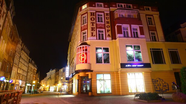 A multi-story hotel with "HOTEL EUROPA" signage, a prominent neon sign, and a visible entrance with glass doors. - Hotel EUROPA (Jelenia Gora)