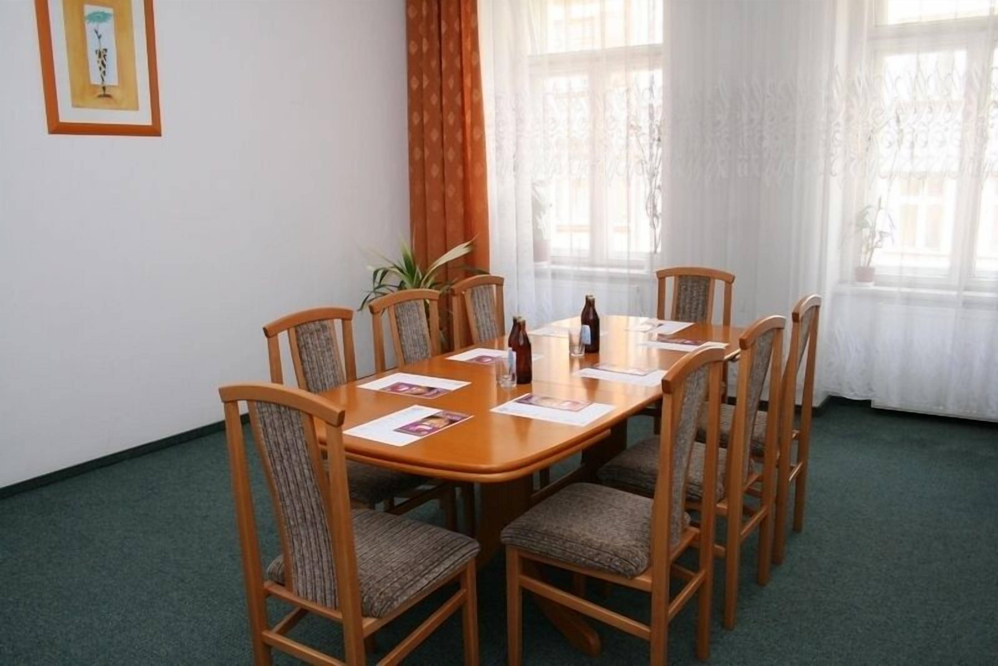 Un'area pranzo con tavolo e sedie in legno, una pianta e una finestra con tende.