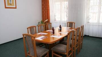 Un'area pranzo con tavolo e sedie in legno, una pianta e una finestra con tende.