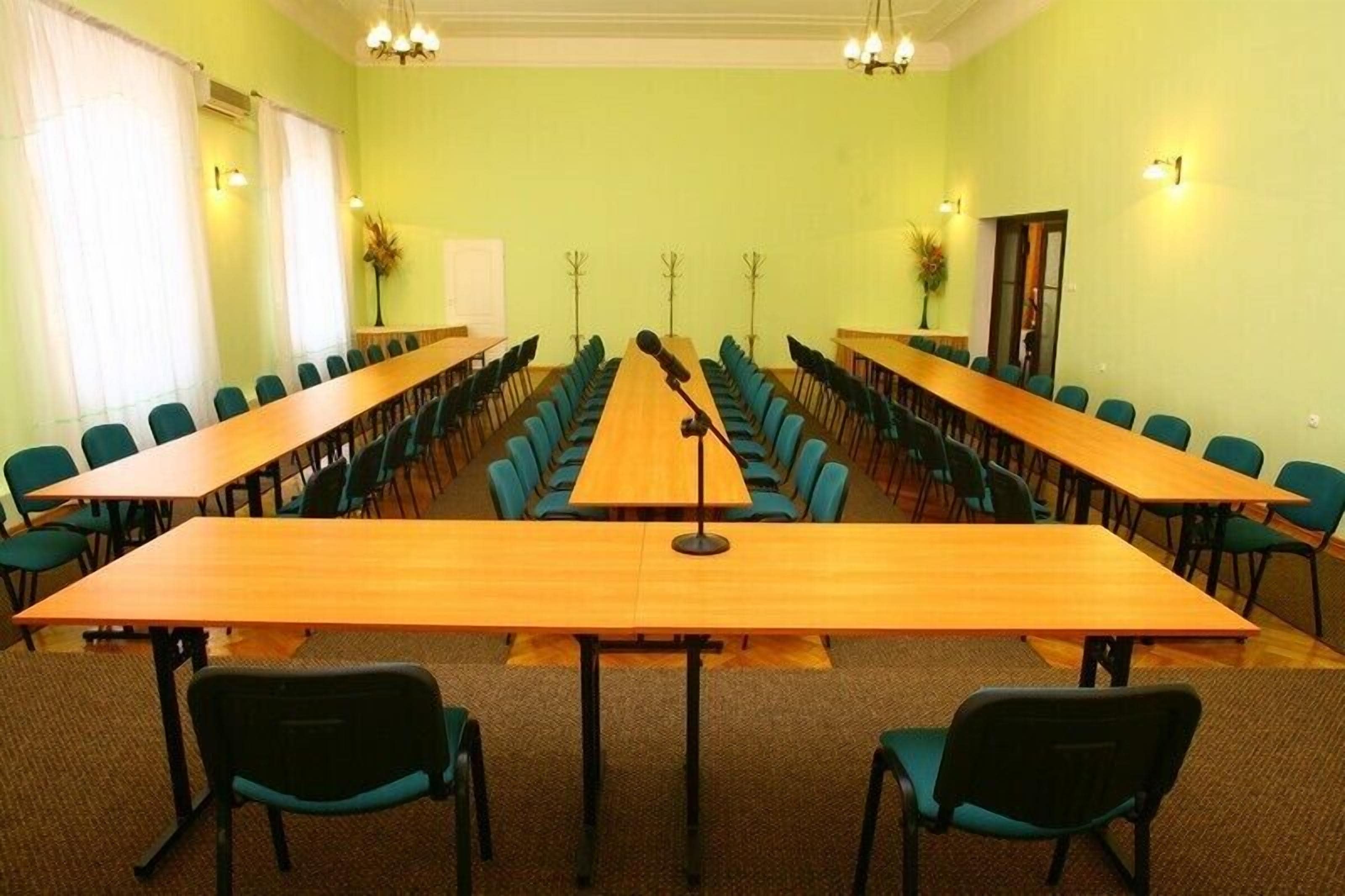 Un salón de conferencias con una larga mesa, varias sillas y un soporte para micrófono.