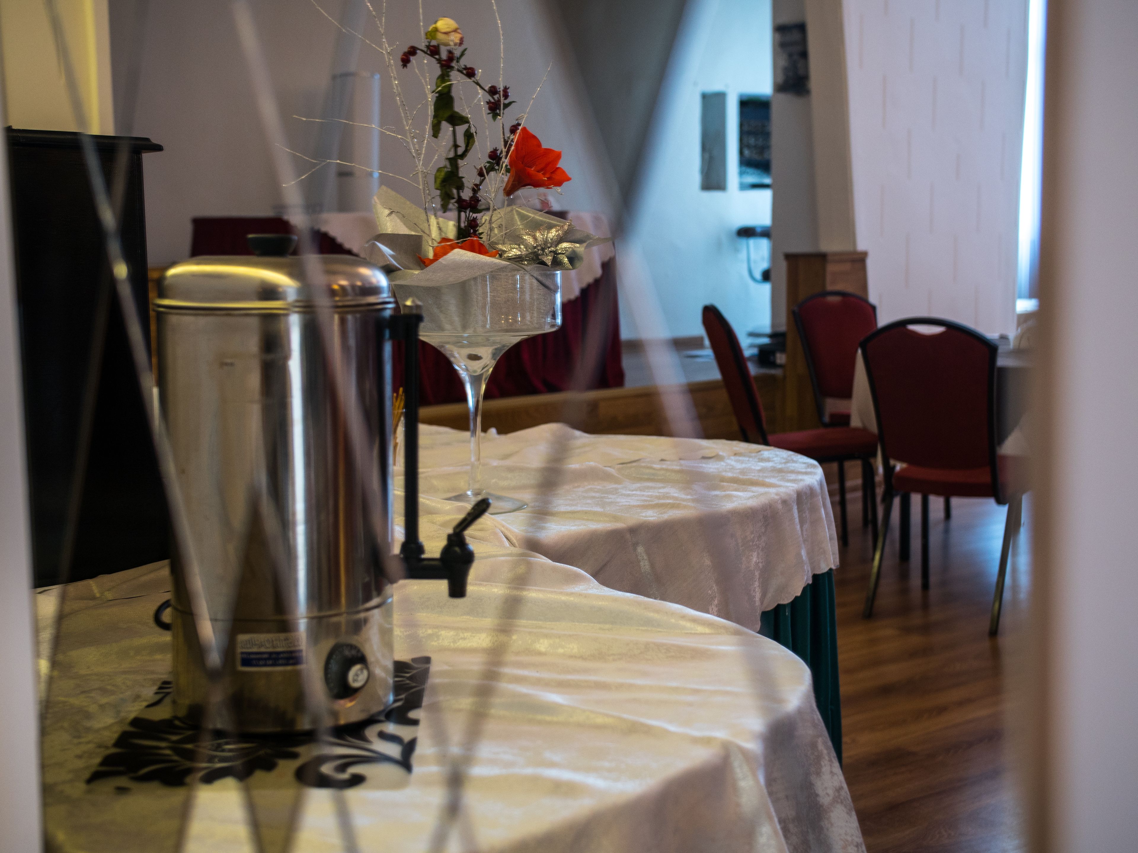 A dining table with a coffee maker and a vase with flowers.