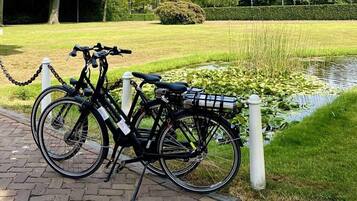 A bicycle parked by a paved path next to a pond with lily pads.