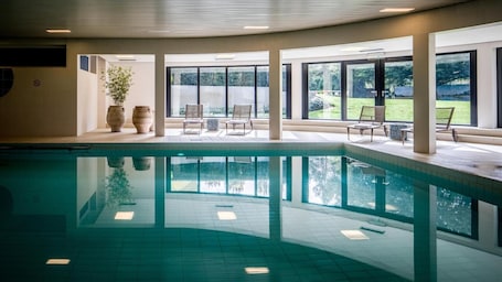 Una piscina techada, sillones reclinables de piscina