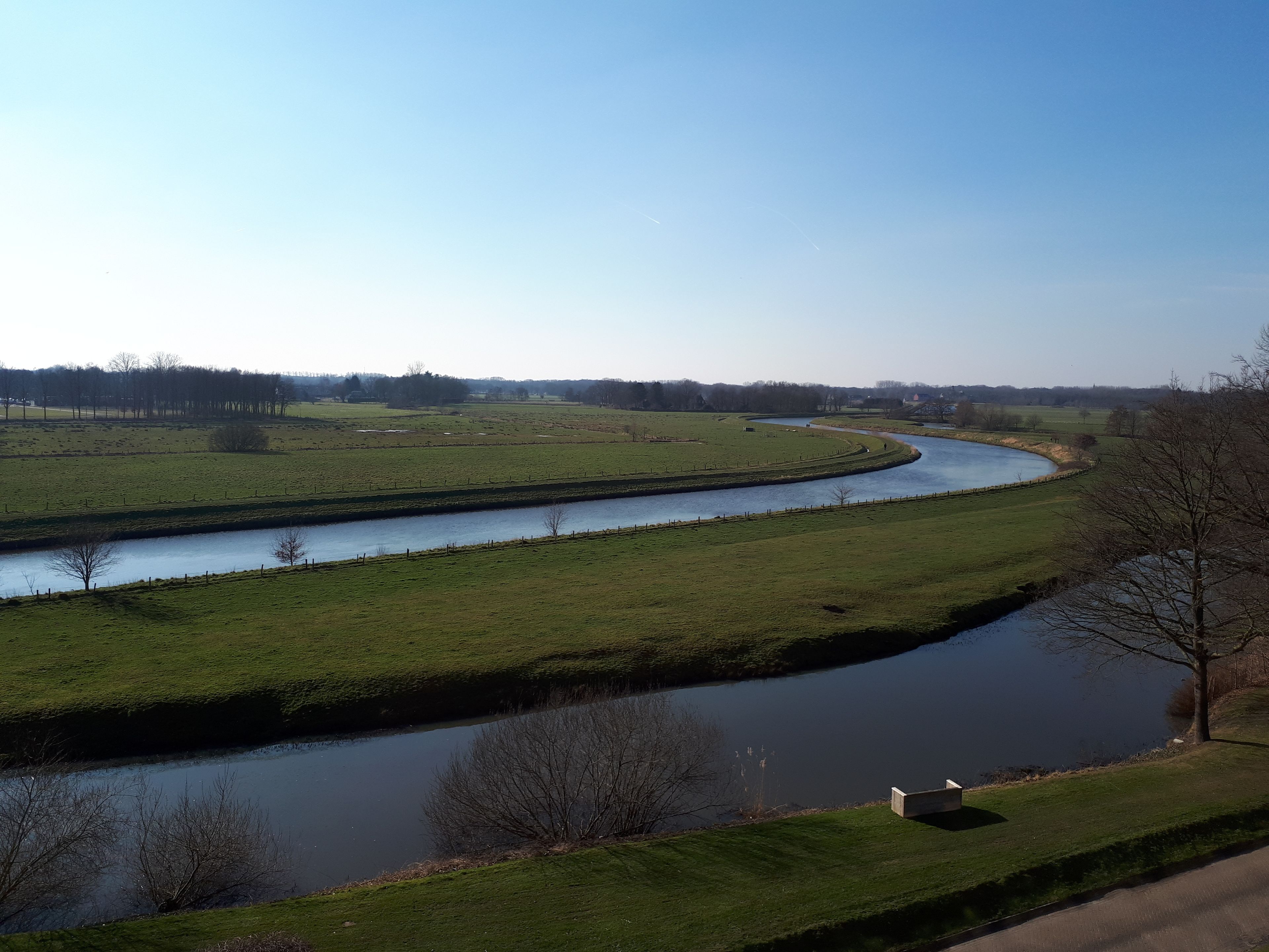 A river meandering through a green landscape with a clear sky.