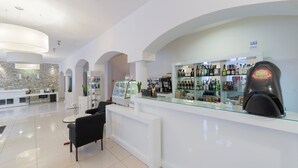 A modern bar area with a glass counter, various liquor bottles, and a coffee machine. - Hotel Impresja (Duszniki Zdroj)