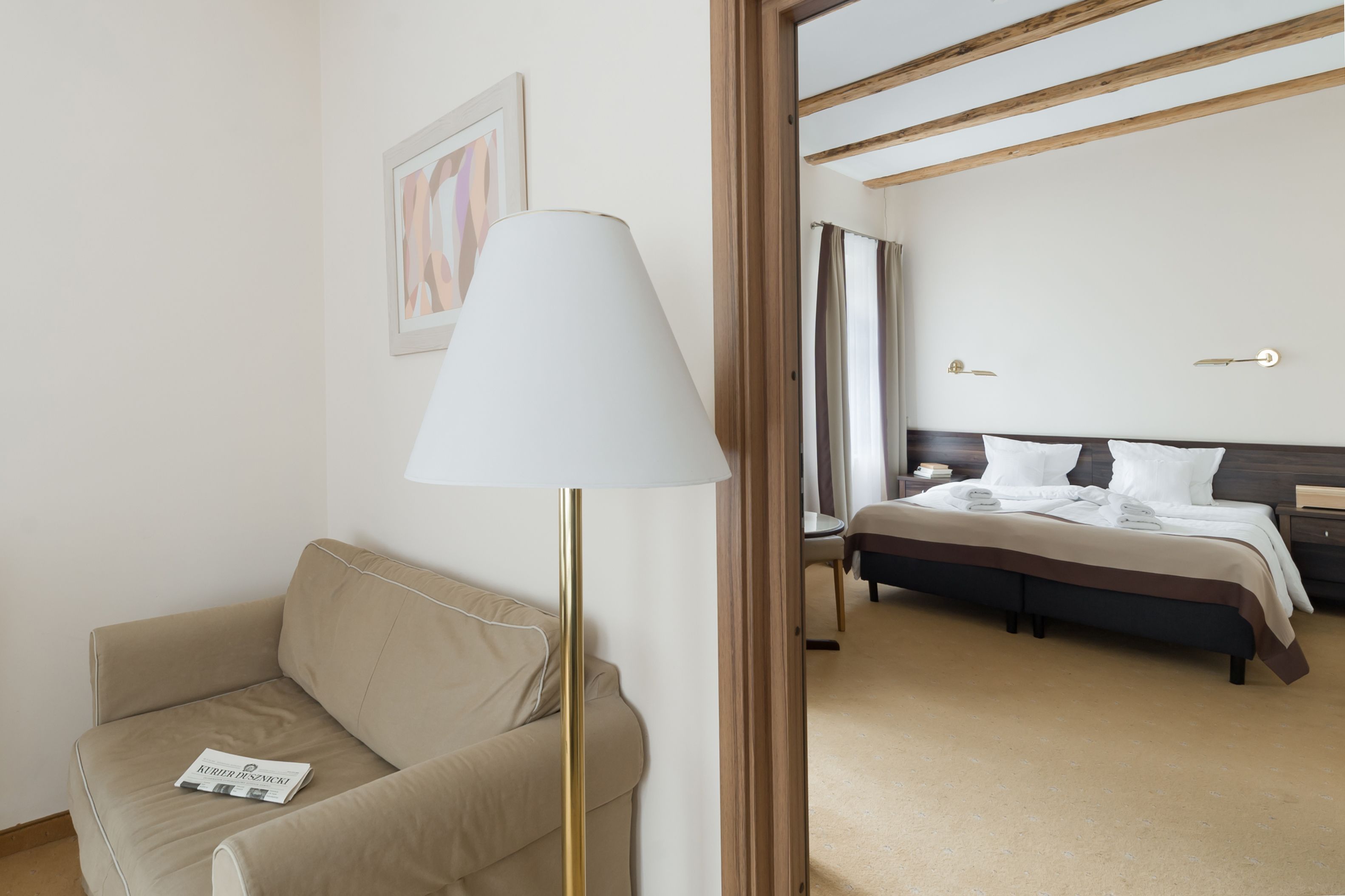 Una habitación de hotel con una cama, una mesita de noche, una lámpara, un sofá y un cuadro en la pared.