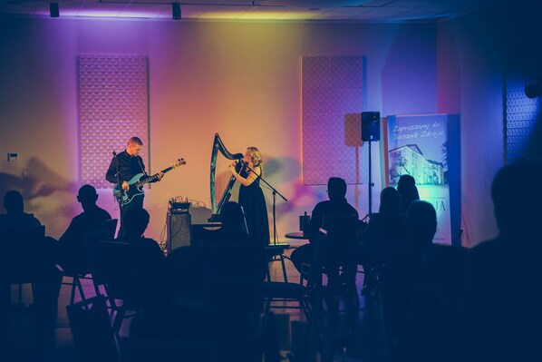 A band performing on stage with a microphone stand and a banner in the background. - Hotel Impresja (Duszniki Zdroj)