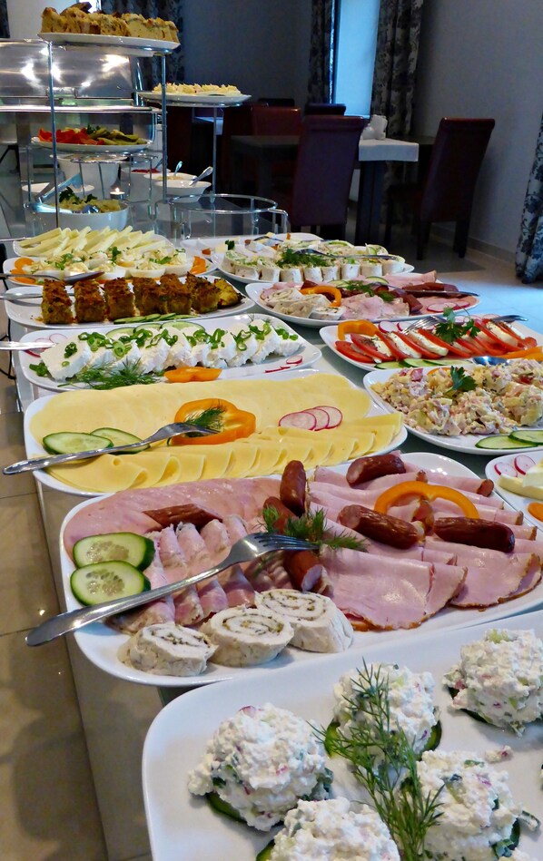 Un bufé con diversos platos, incluyendo carnes, quesos y ensaladas.