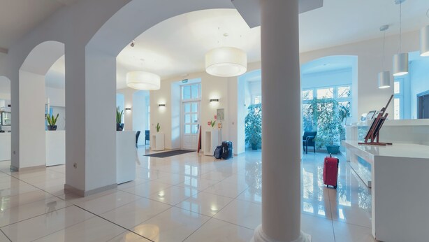 A spacious lobby with high ceilings, large windows, and a central reception desk. - Hotel Impresja (Duszniki Zdroj)