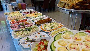 Un buffet proposant une variété de plats, notamment des salades, des viandes et des desserts.