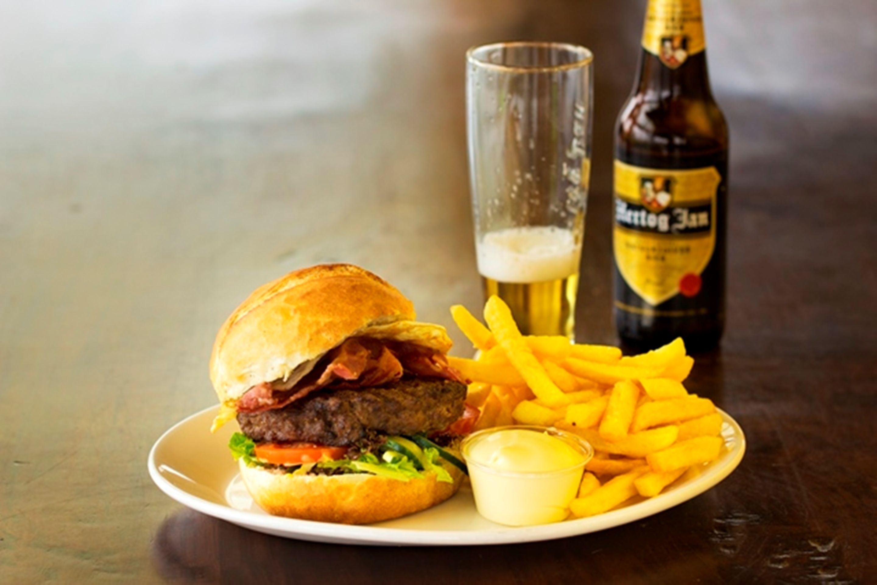 A plate with a burger, fries, and a drink.