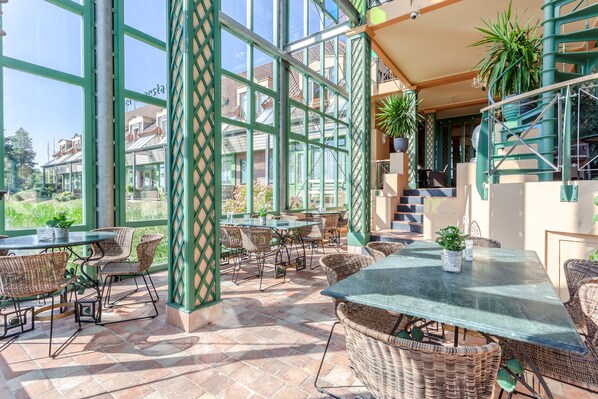 An outdoor patio area with wicker furniture, glass tables, and potted plants. - HarTeluk Joure (Joure)