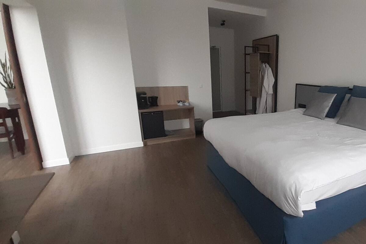 A bedroom with a large bed, a desk, and a wardrobe.