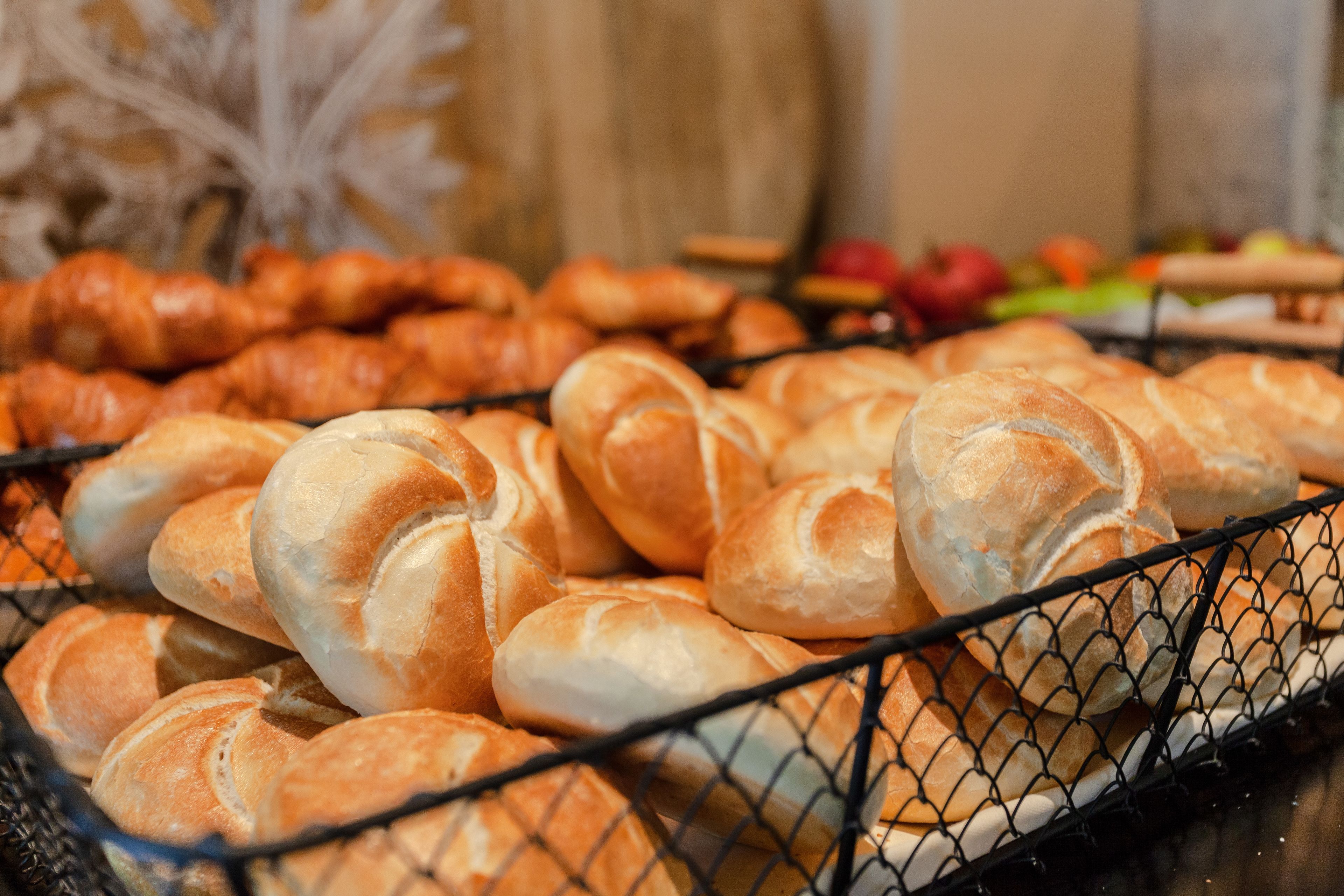 A basket of various types of bread, including croissants and baguettes, displayed in a wire basket.