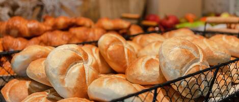 A basket of various types of bread, including croissants and baguettes, displayed in a wire basket.