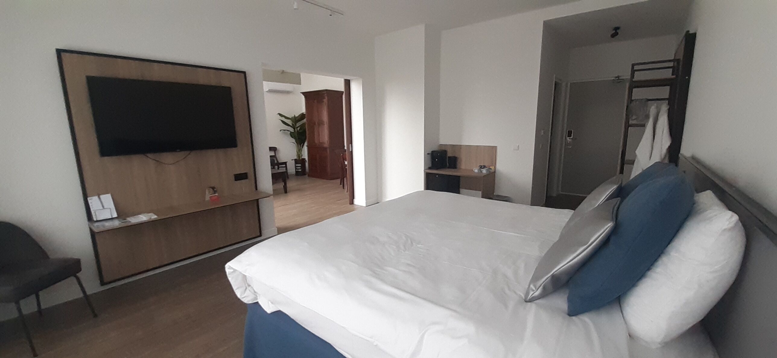 Une chambre d’hôtel équipée d’un lit, d’un bureau, d’une chaise, d’un téléviseur fixé au mur et d’une armoire.