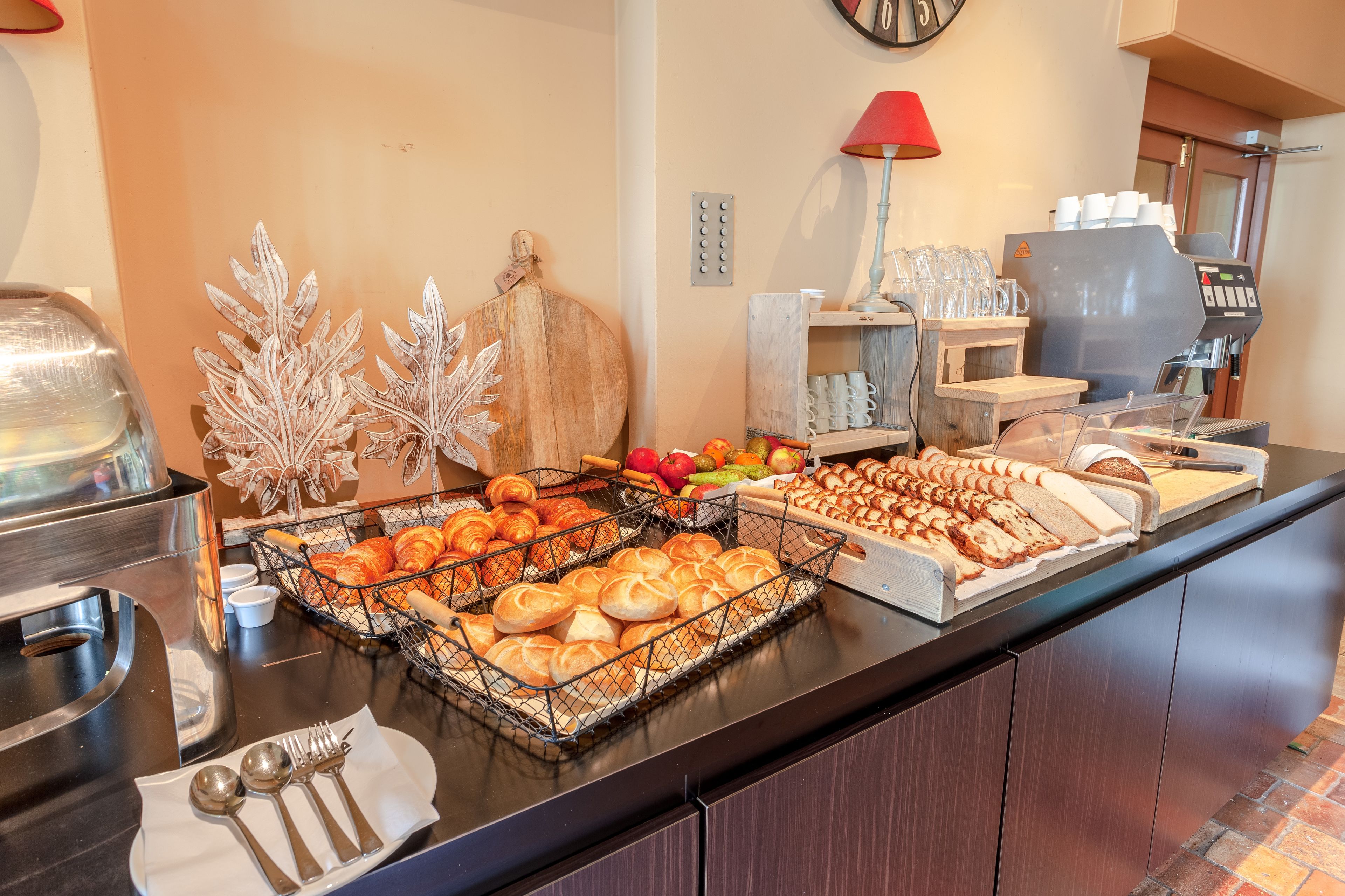 Un buffet proposant une variété de plats, notamment des pâtisseries, des fruits et du pain.