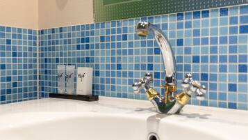 Ein Badezimmer mit einem weißen Waschbecken, einem Chromarmaturen und blauen Mosaikfliesen an der Wand.