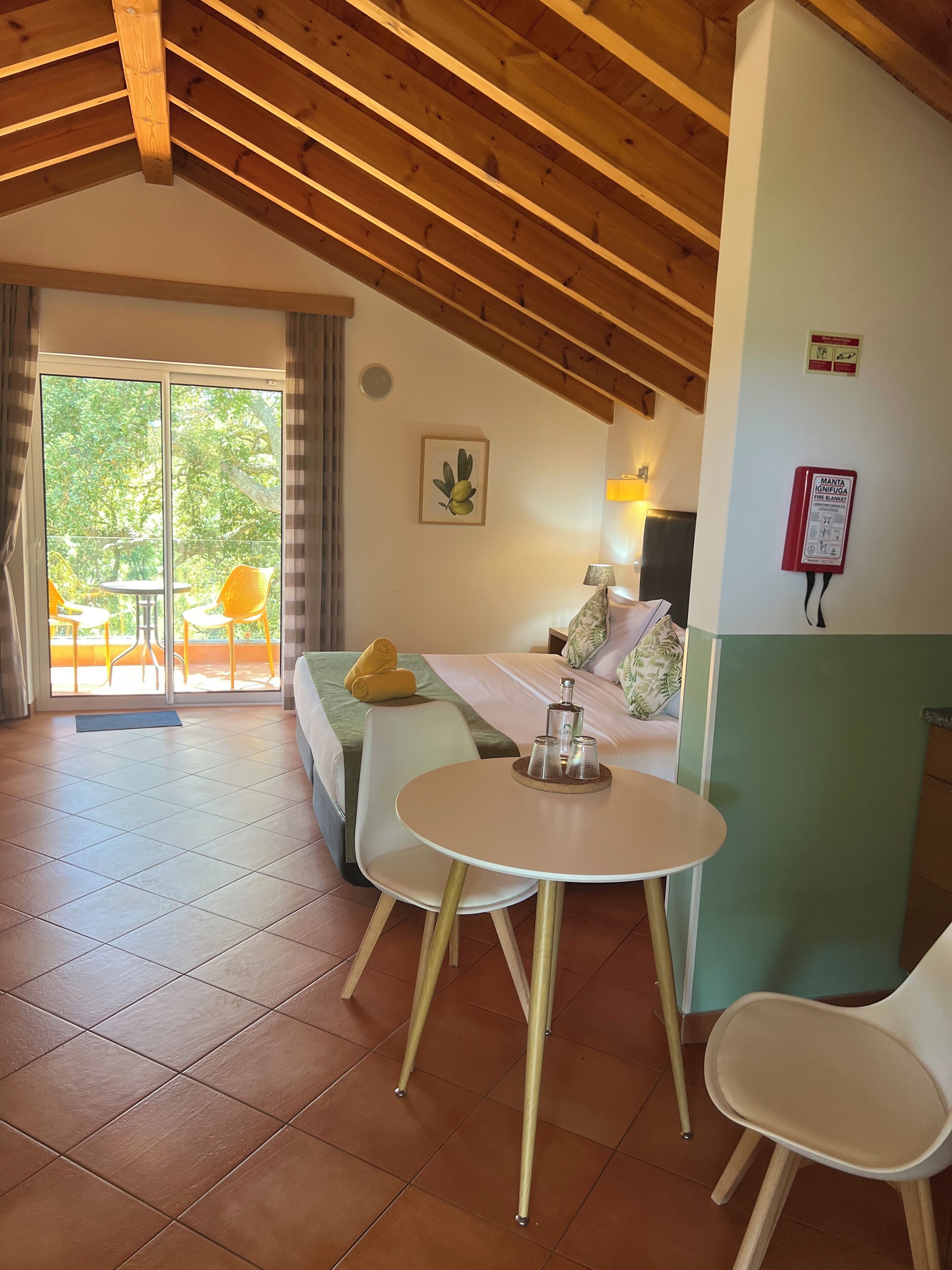 Una habitación acogedora con una cama, una mesita con tazas, una silla y vistas al exterior.