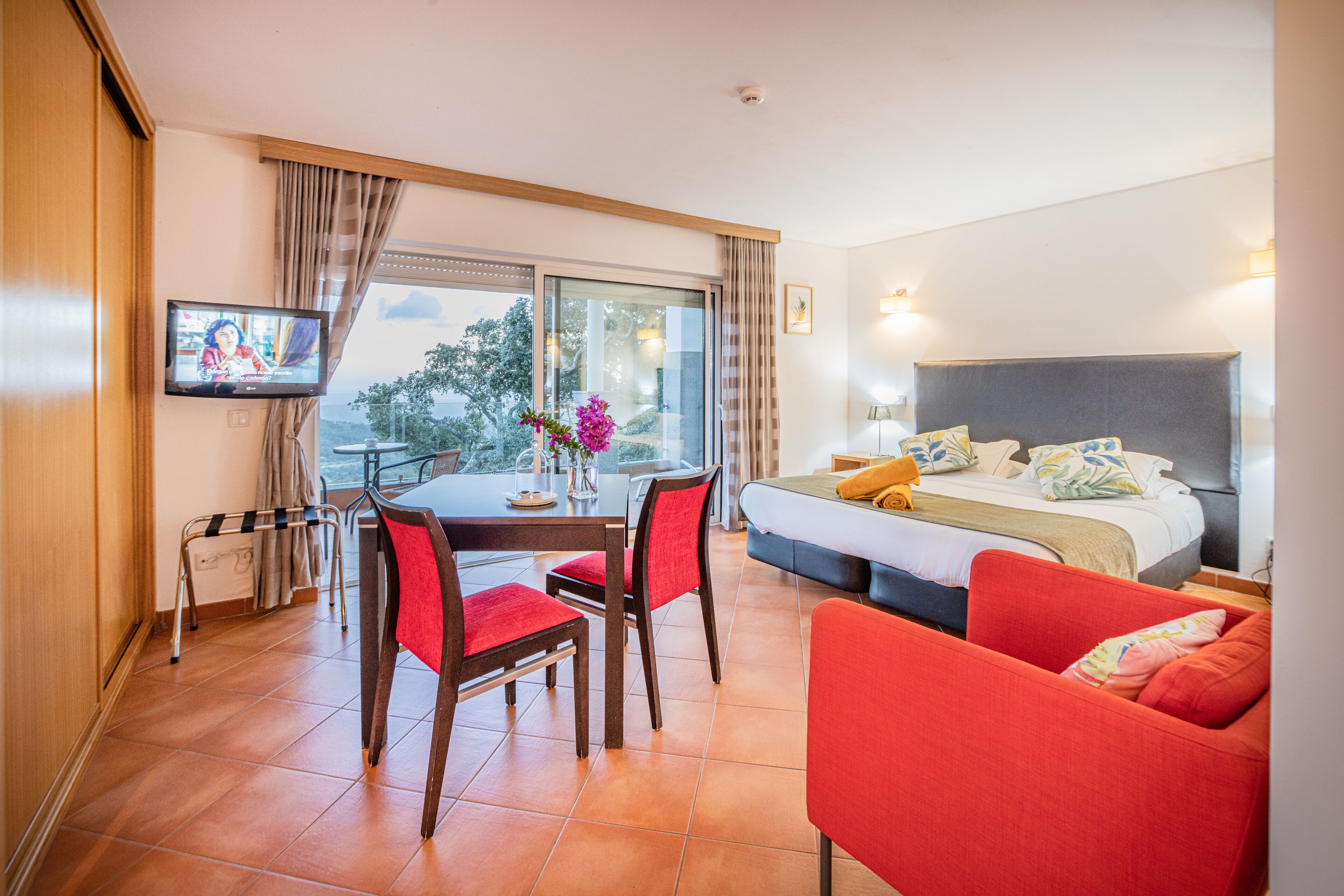 Une chambre d’hôtel comprenant un lit, une télévision, une table à manger avec des chaises et un balcon avec vue.