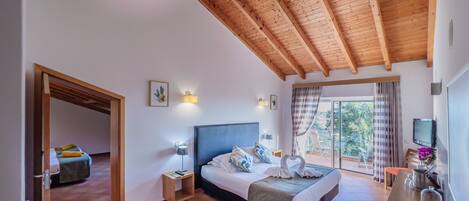 Ein Schlafzimmer mit Bett, Nachttischen, einem Fernseher und einem Balkon mit Blick.