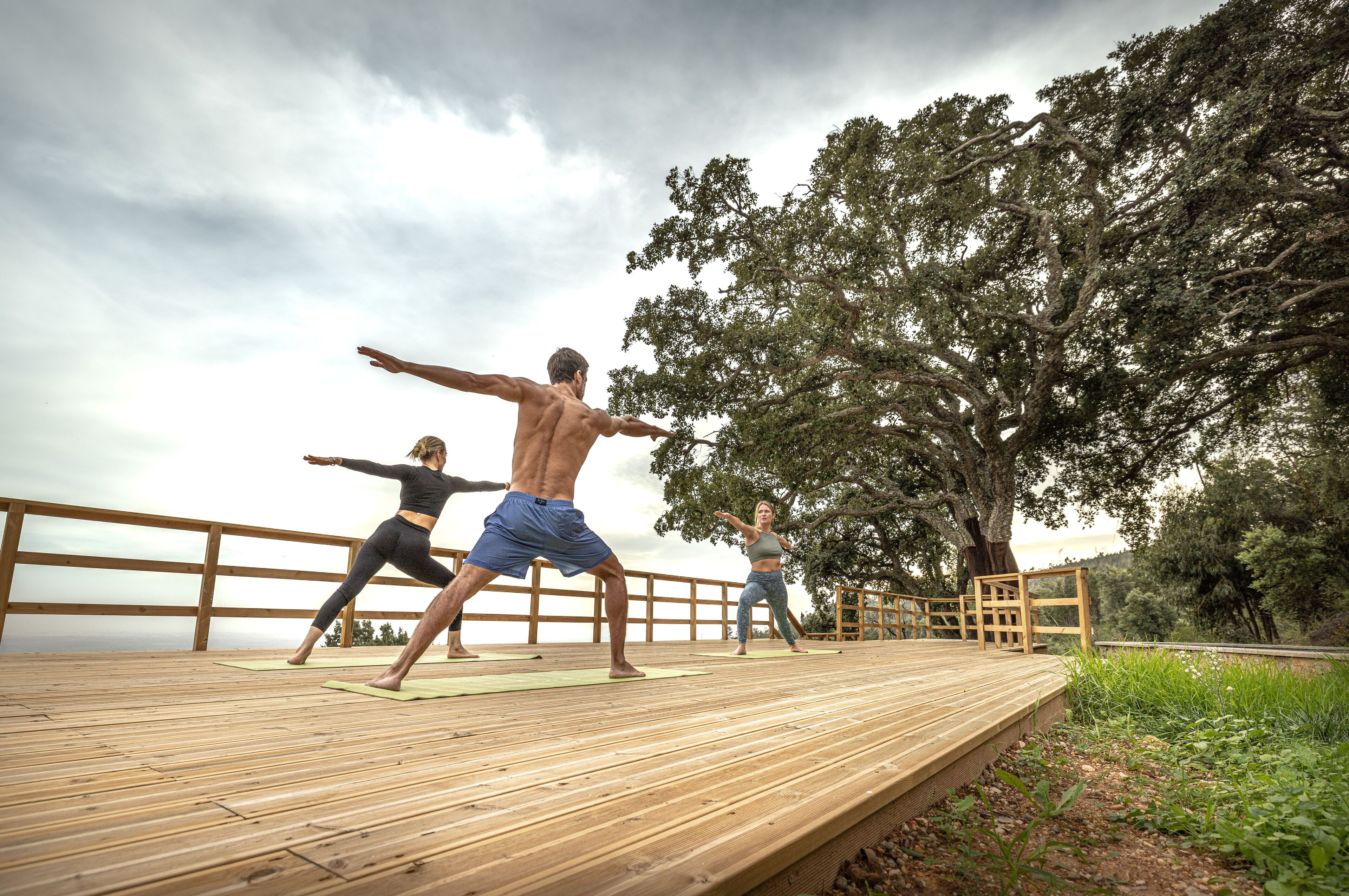 Una terraza de madera con gente practicando yoga.