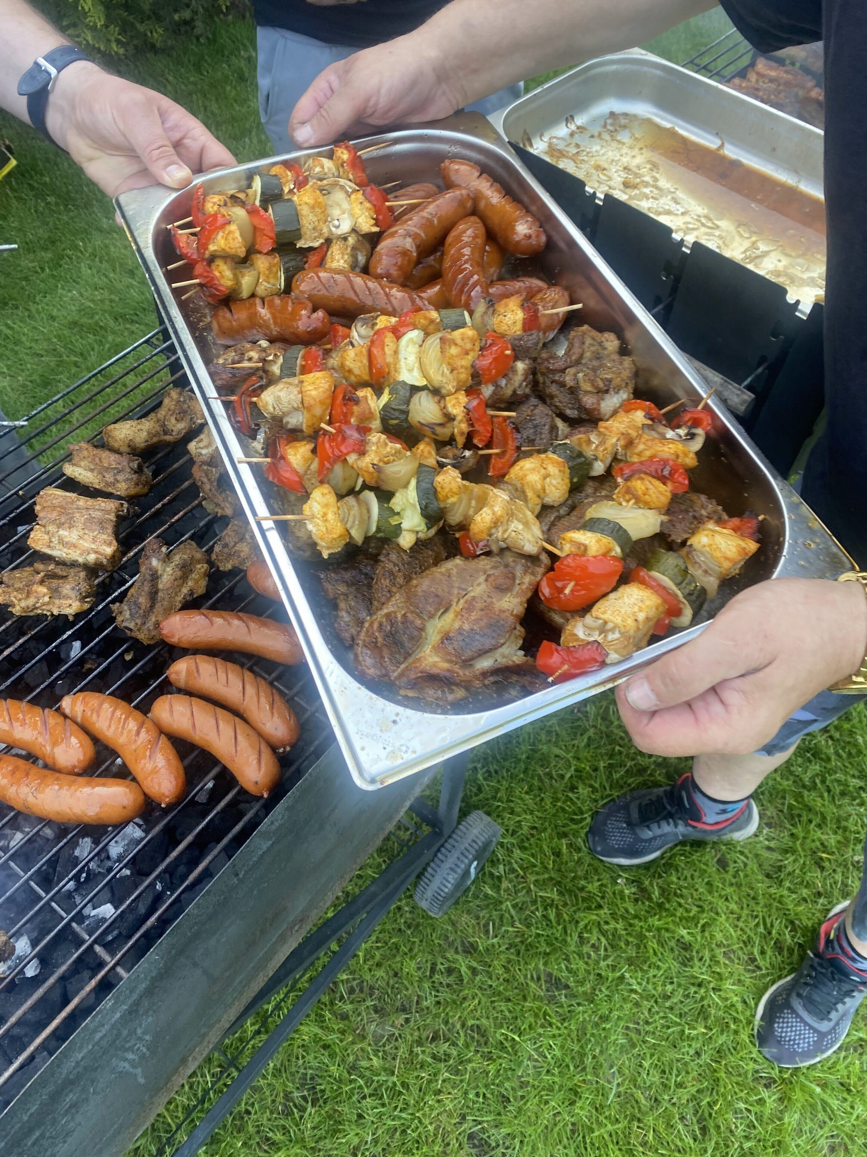 Una bandeja con carnes y verduras a la parrilla, incluyendo salchichas y brochetas con pimientos y cebollas.