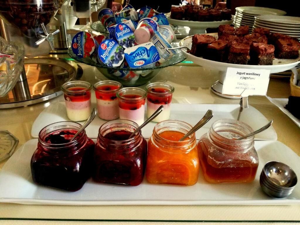 A buffet with various food items including jars of jam, yogurt, and desserts.