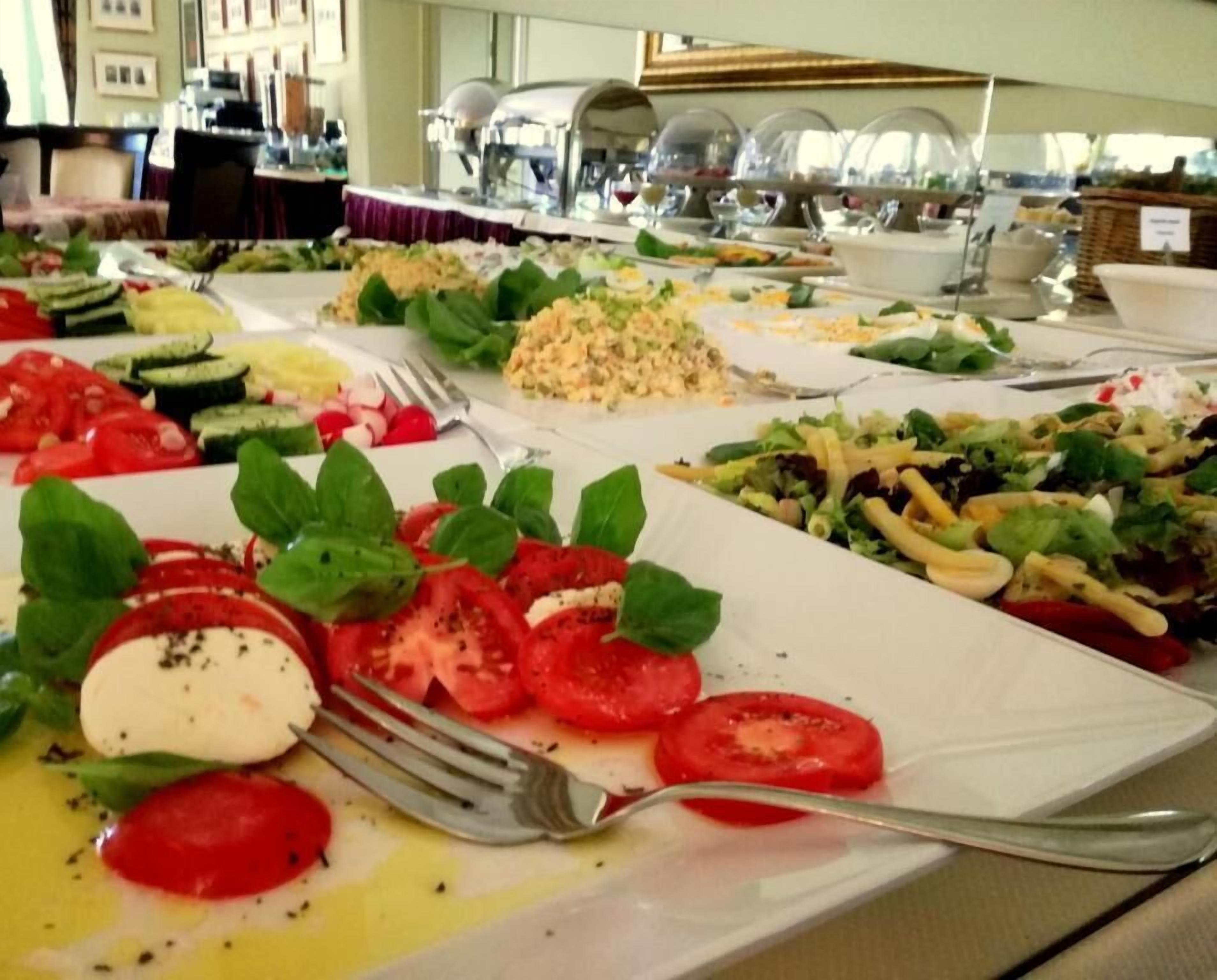 A buffet with various dishes including a tomato and mozzarella salad, a cucumber salad, and a pasta salad.