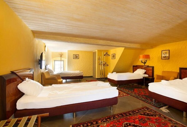 Una habitación de hotel con tres camas, techo de madera y un ventanal grande.