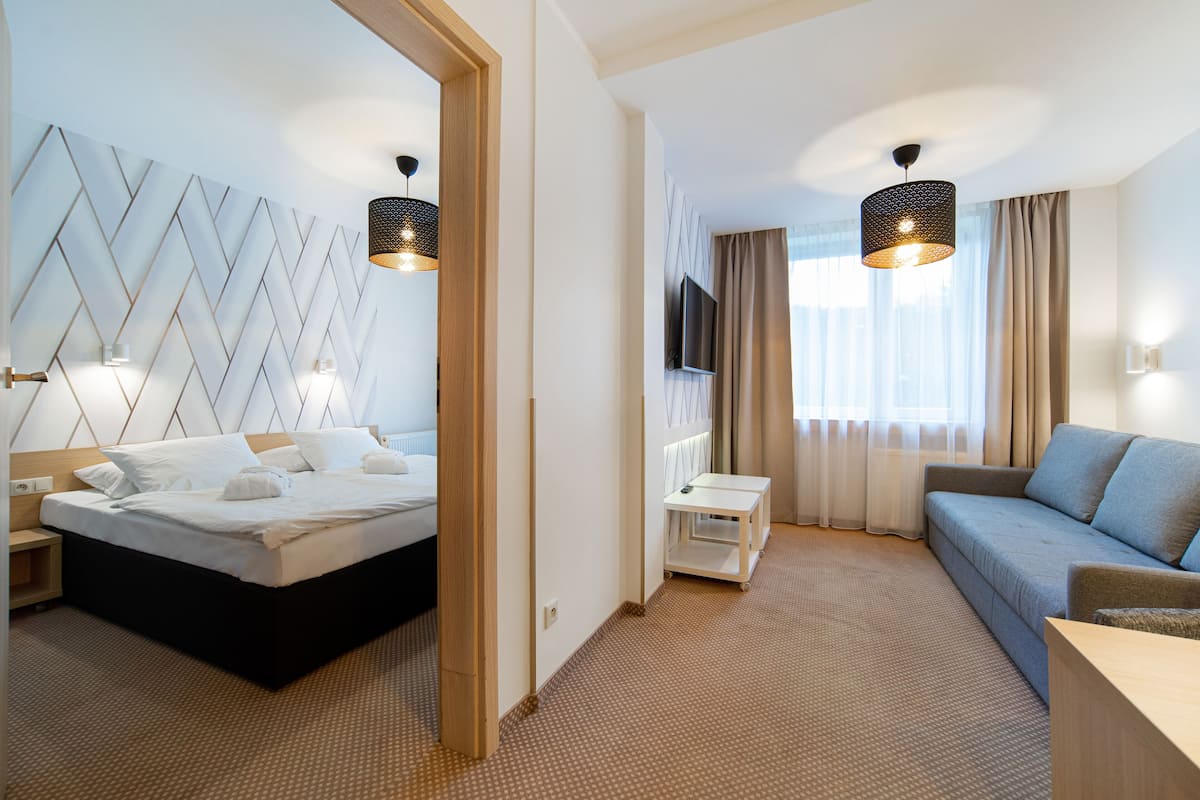 A hotel room with a bed, a sofa, a TV, and a small table.